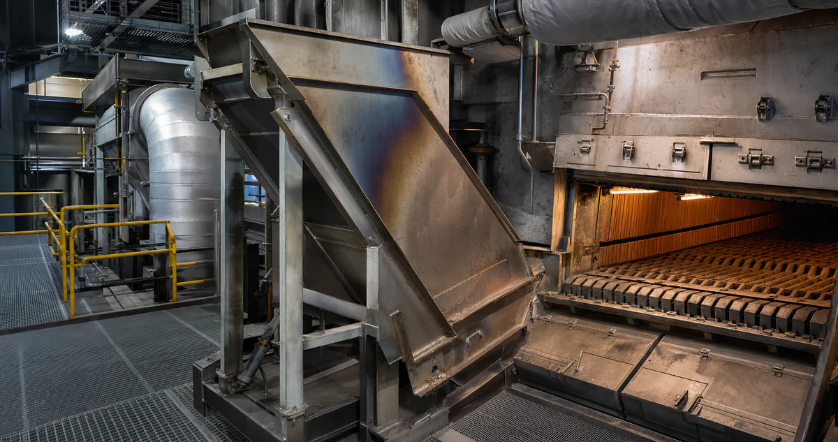 Waste-to-energy furnace service area with a supported chute, grate and insulated duct