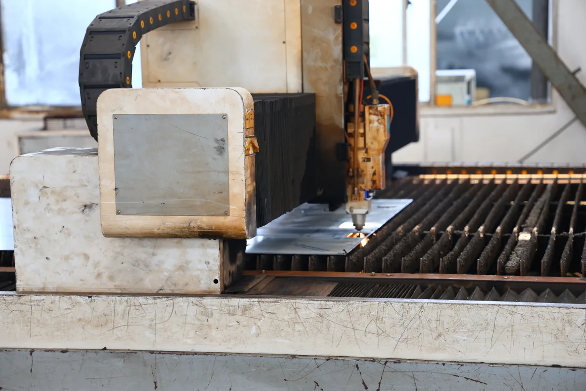 Enclosed fiber-laser head cutting a supported stainless steel plate